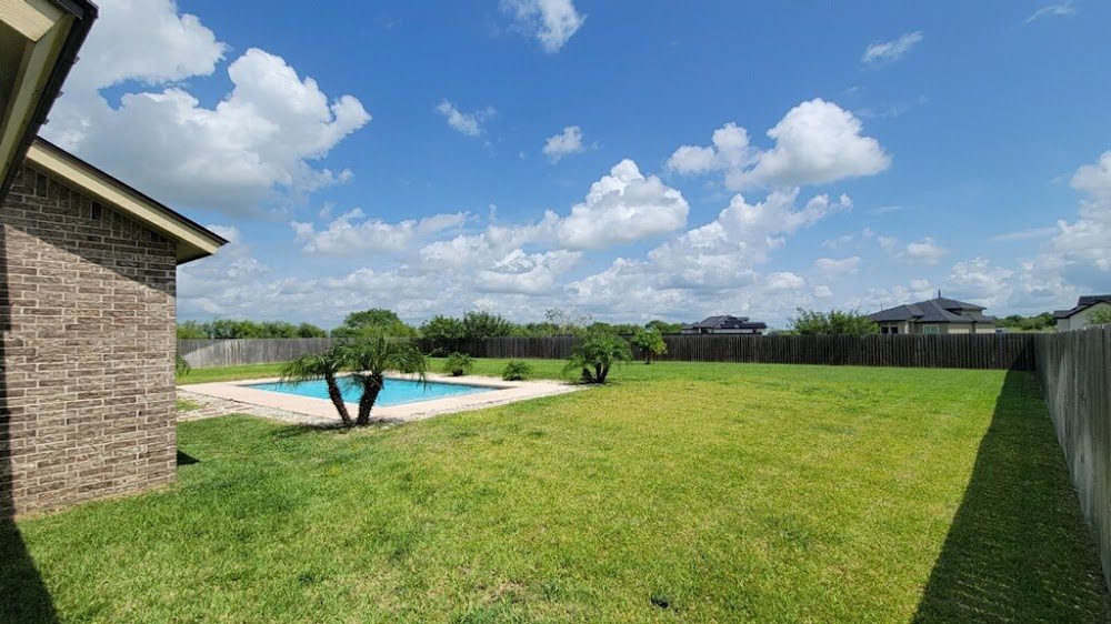 Backyard lawn cut and trimmed around a pool