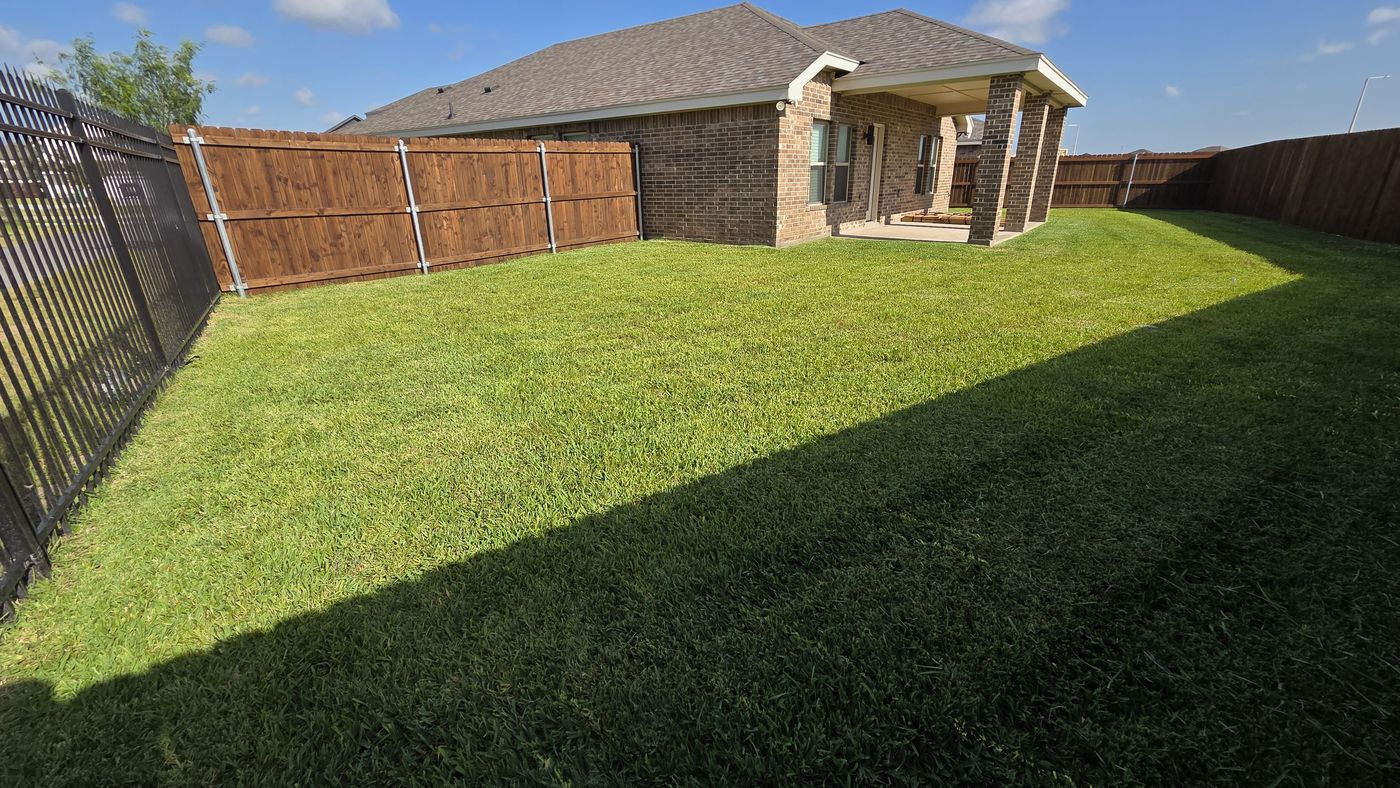 Brick home backyard freshly cut along the fence line